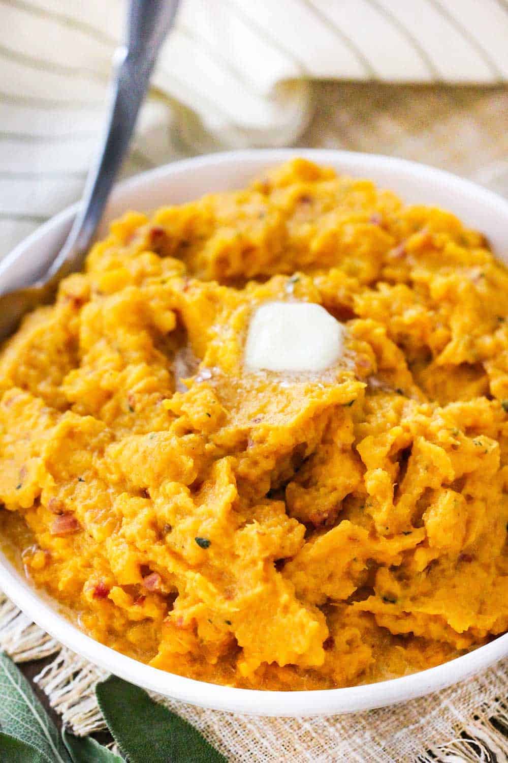 A white bowl holding pressure cooker mashed butternut squash with a tab of butter on top. 