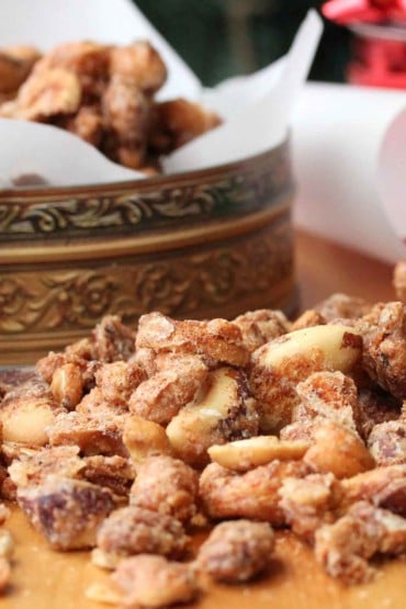 Naughty and Nice Spiced Nuts on a wood cutting board next to a tin with nuts