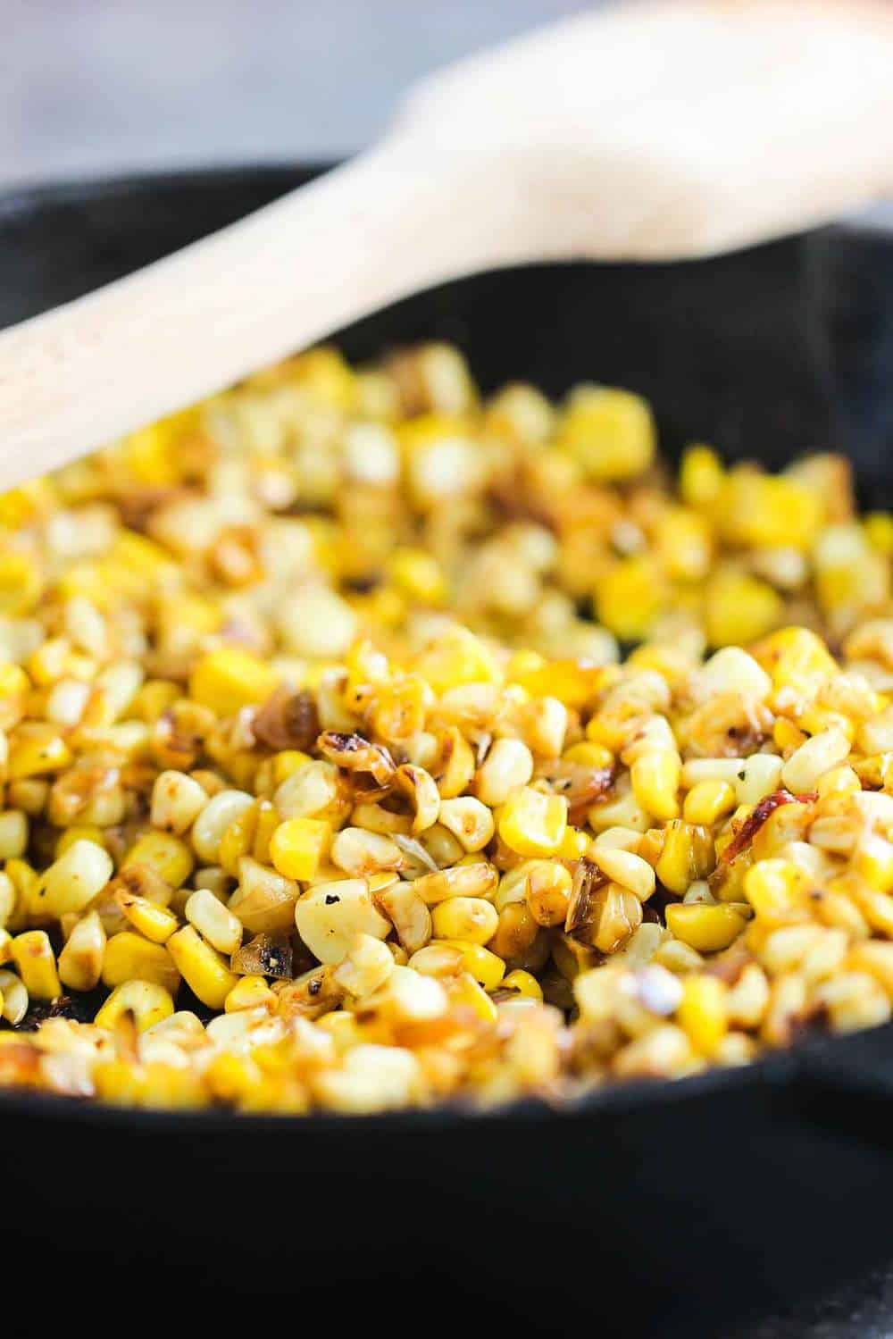 A close-up view of corn kernels that have been roasted in a cast-iron skillet