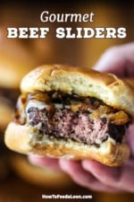 A close-up view of a person holding a beef slider that has a bite taken out of it.