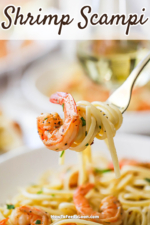 A fork being used to hold up cooked pasta that is twirled on the utensil with a sautéed shrimp also attached.