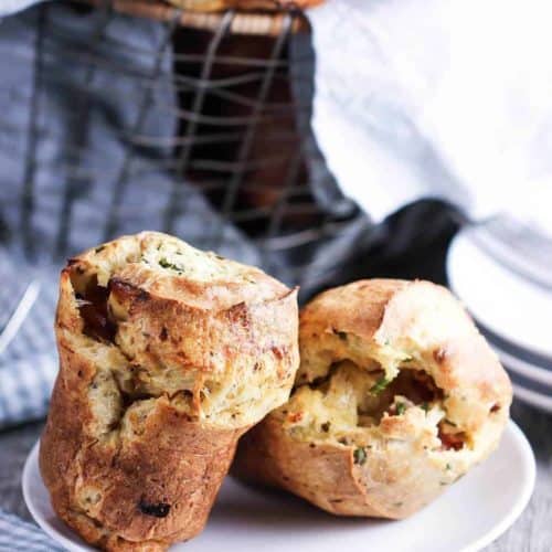 Ham and Gruyere Savory Popovers on a white plate next to a blue and white patterned napkin