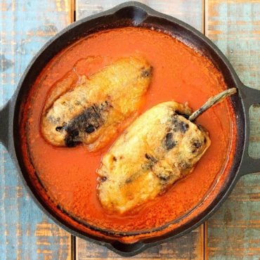 Chile rellenos in a black cast iron skillet.