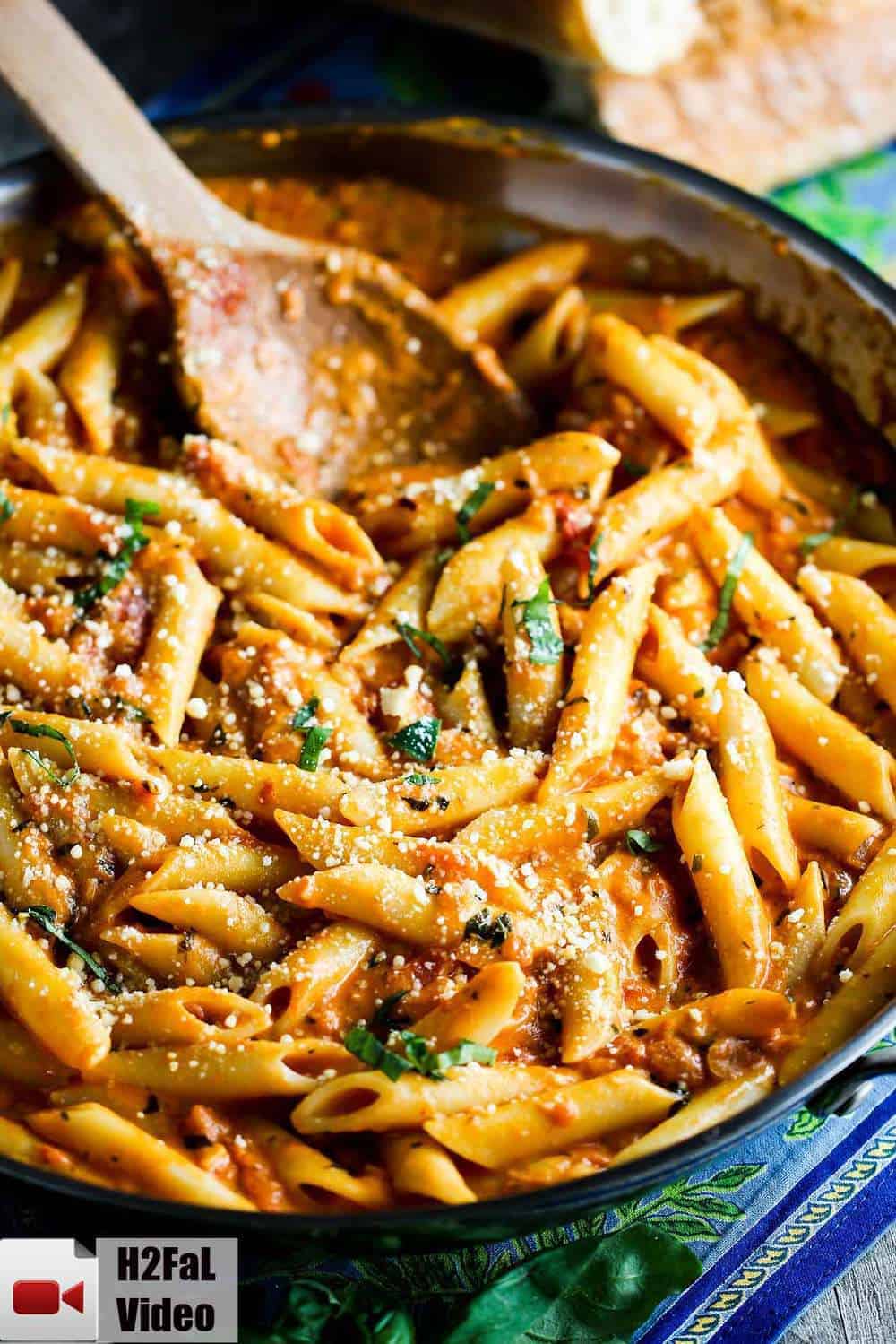 Penne alla Vodka in a skillet with a wooden spoon in the pasta. 