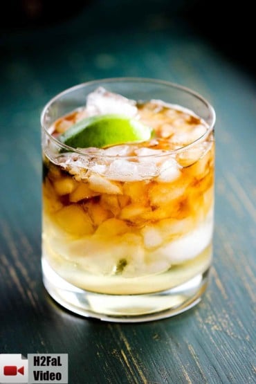 This is a dark and stormy cocktail with chipped ice, rum, ginger beer and a lime in a rocks glass.