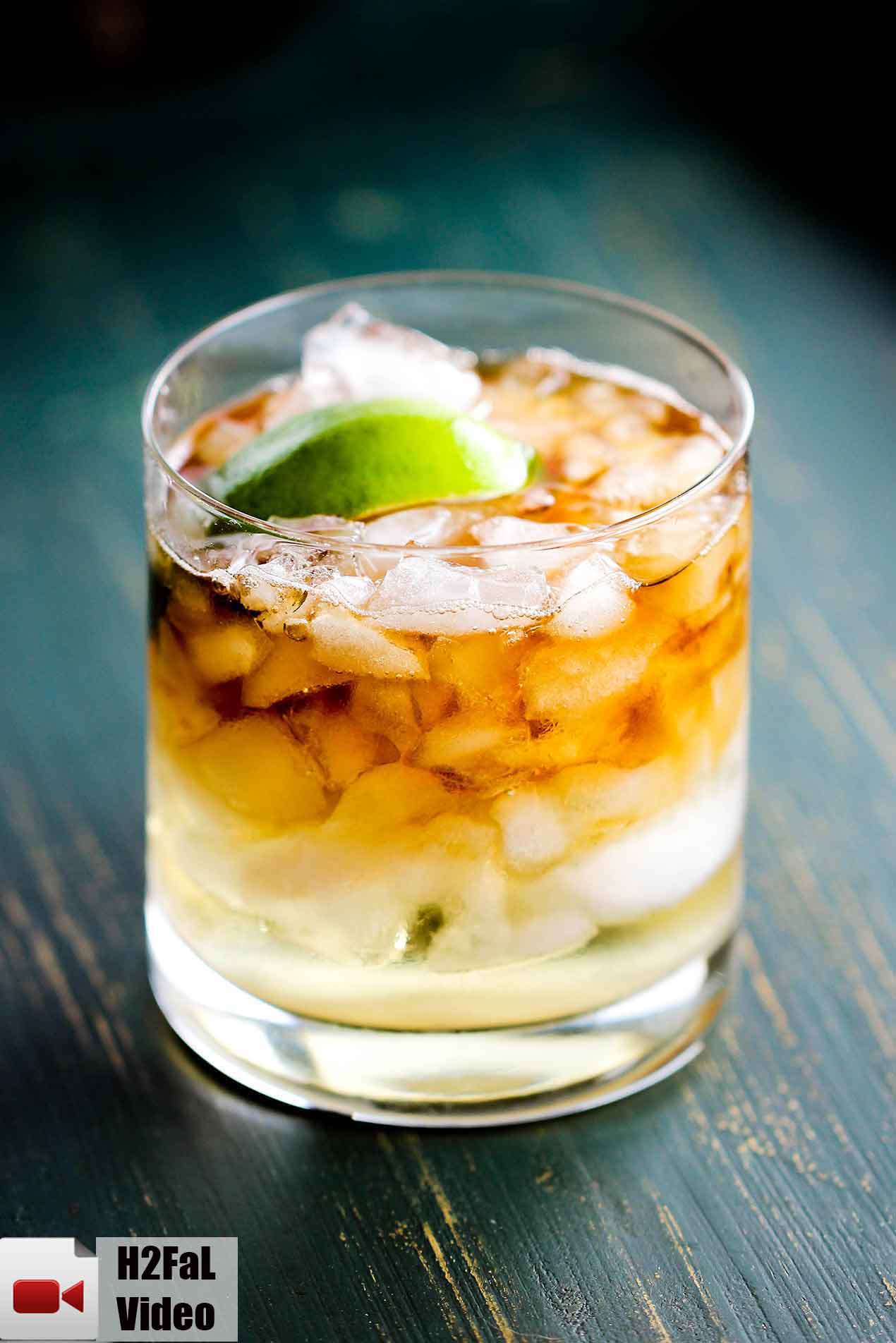 This is a dark and stormy cocktail with chipped ice, rum, ginger beer and a lime in a rocks glass. 