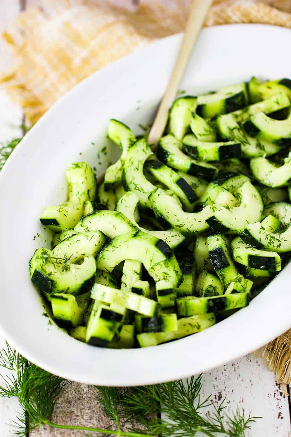 A white bowl of freshly prepared cucumber and dill salad. 