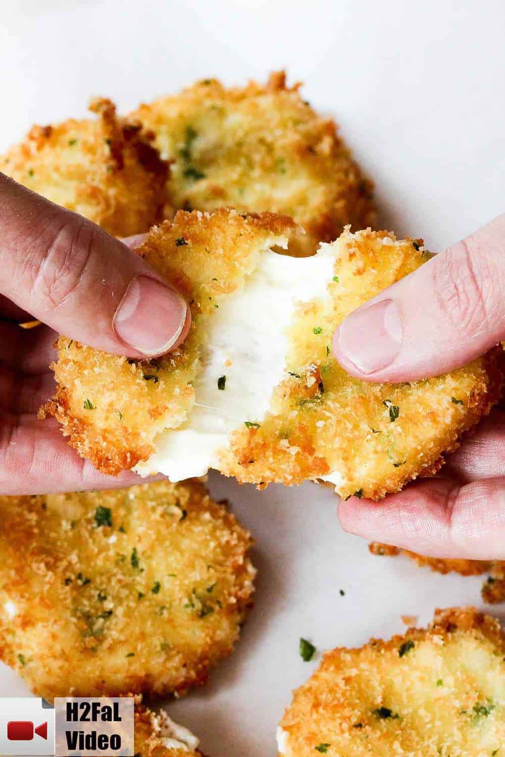 Fried mozzarella being pulled apart to two hands