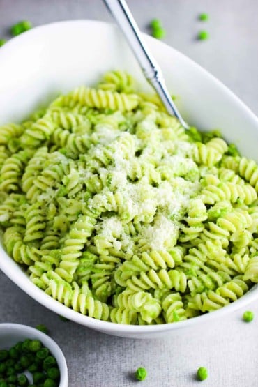 Fresh pea pesto pasta in a white serving bowl with a spoon