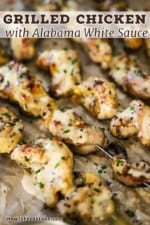 A close-up view of a grilled chicken skewers that have a layer of Alabama white sauce drizzled over the top.