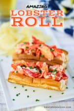 Two lobster rolls sitting on a rectangular white plate with snipped chives sprinkled over the top.