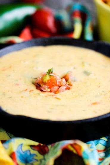 Classic Tex-Mex Queso in a cast iron dish with pico de gallo on top.