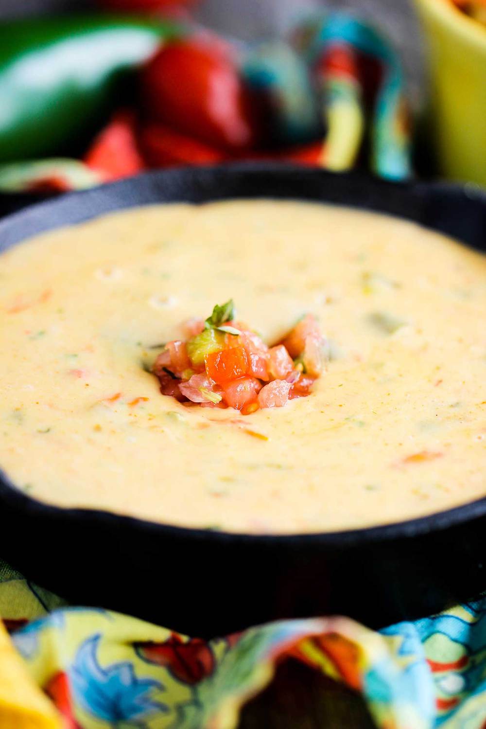 Classic Tex-Mex Queso in a cast iron dish with pico de gallo on top. 