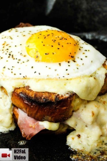 Croque Madame sandwich in a cast iron skillet with melting cheese