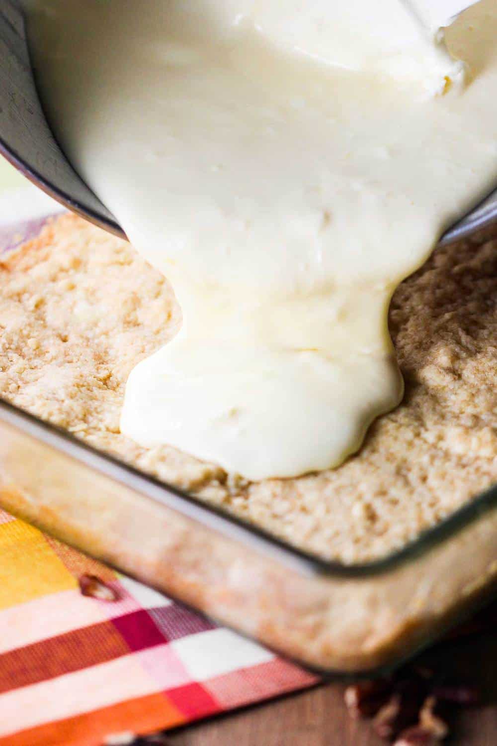 cream cheese batter pouring onto crust for cream cheese apple bars