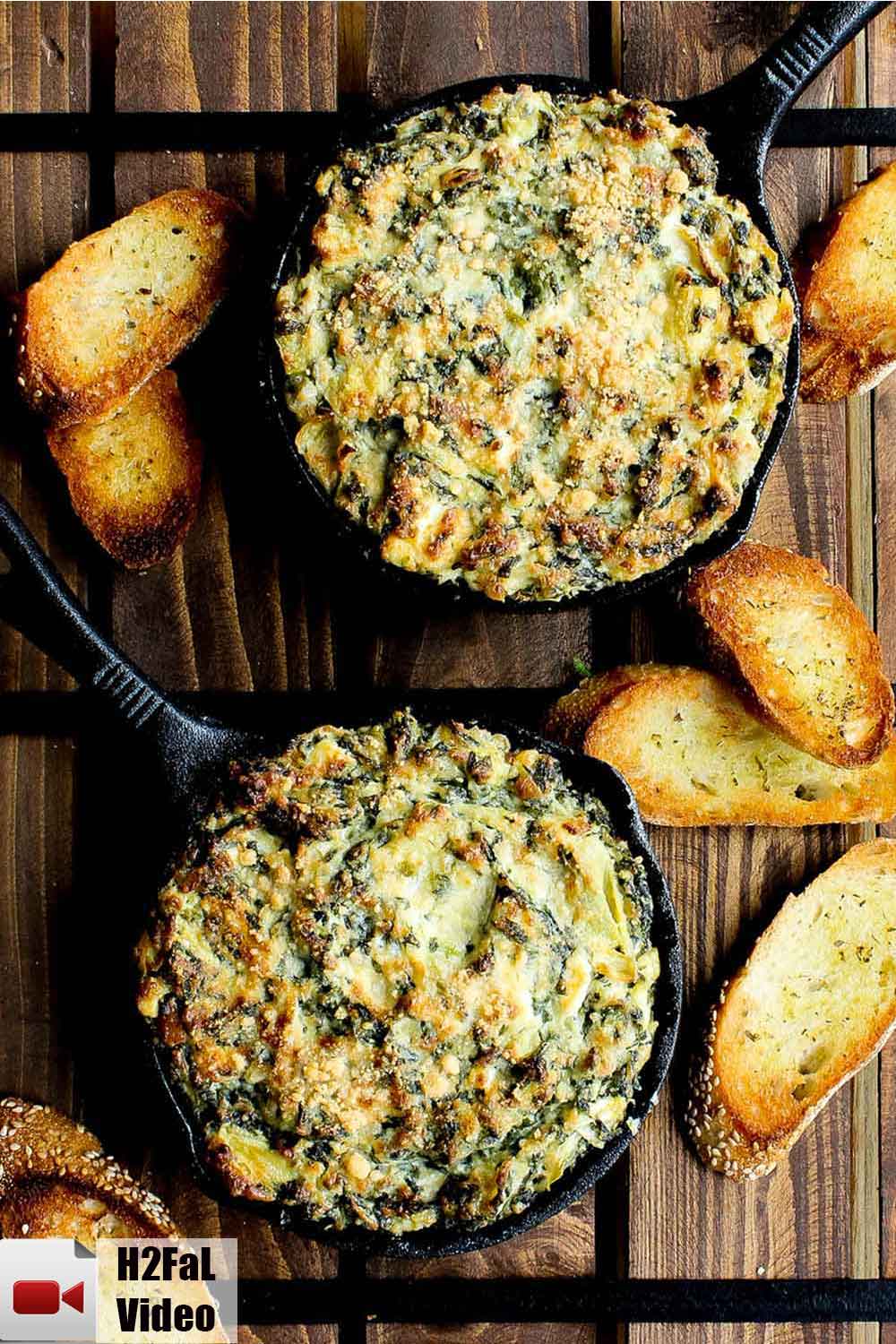 Spinach and artichoke dip in two small cast iron skillets on a wooden table. 