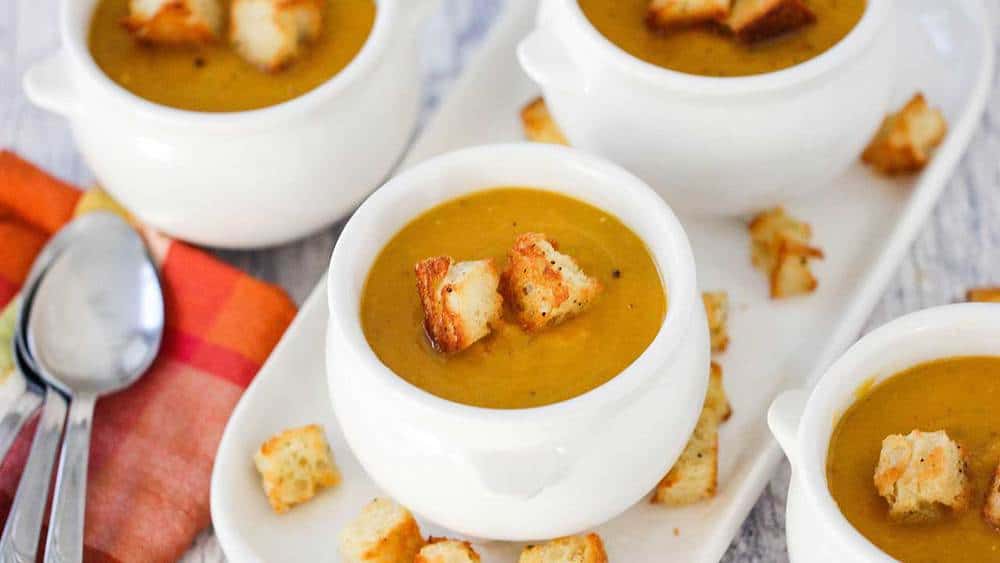 A close-up view of a small crock holding a serving of butternut squash soup. 