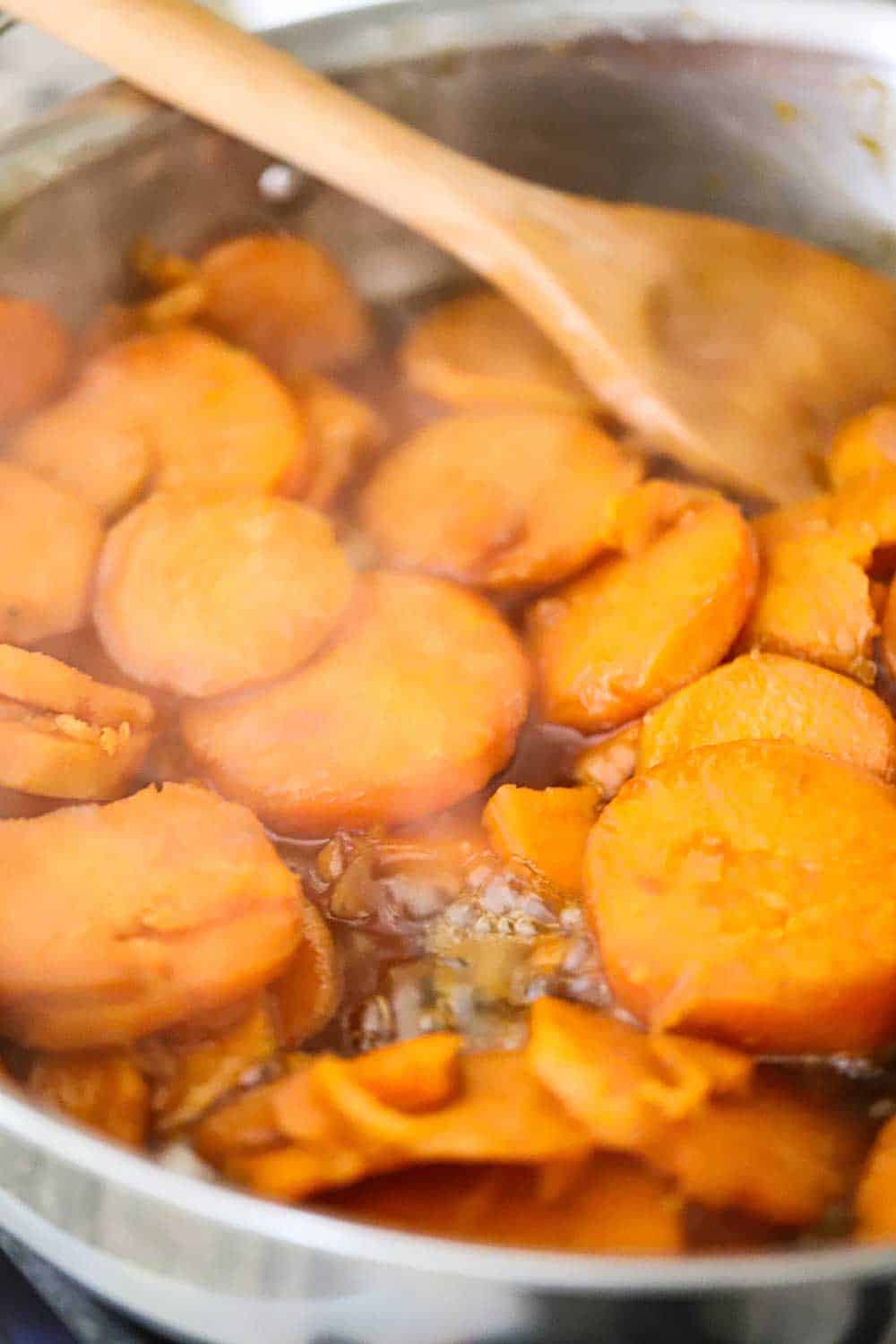 A large silver saucepan filled with simmering candied yams. 