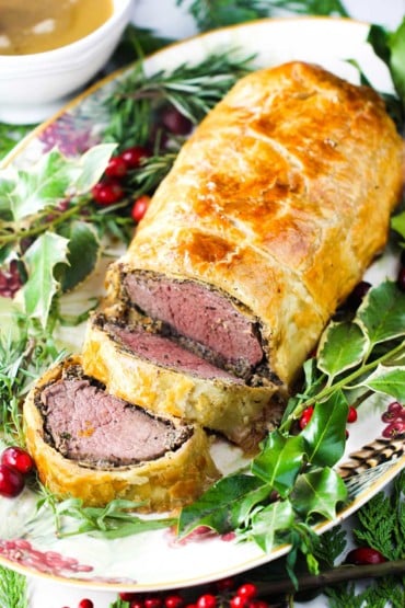 Classic Beef Wellington on a platter with Christmas holly around it
