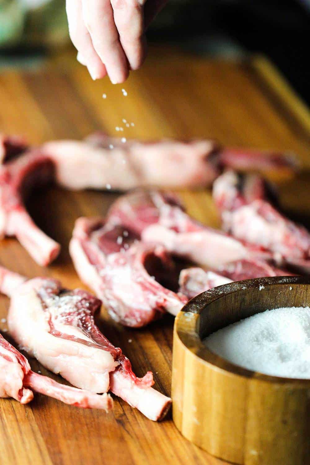 Lamb lollipops being sprinkled with salt