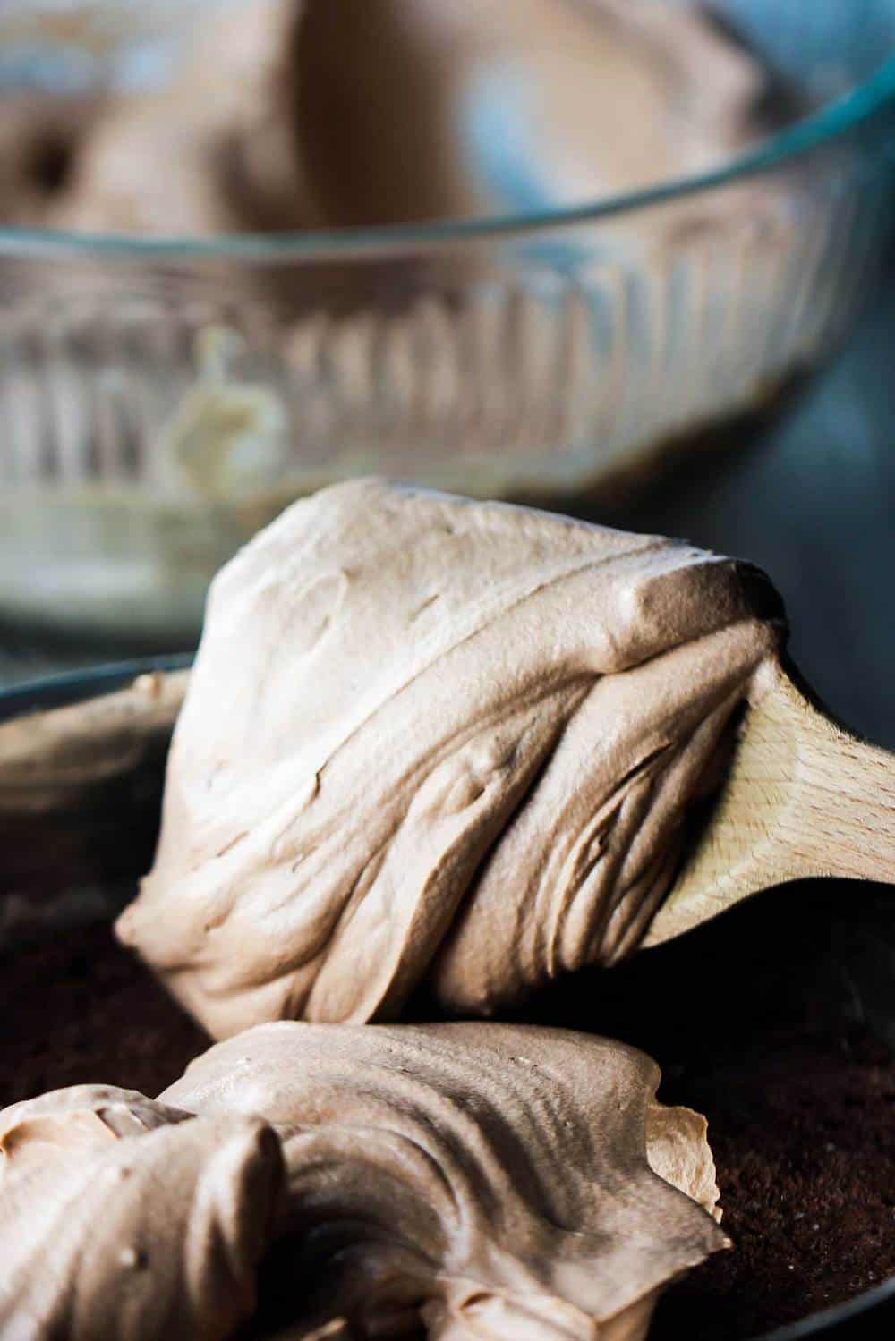 Chocolate mousse on a wooden spoon in a glass bowl