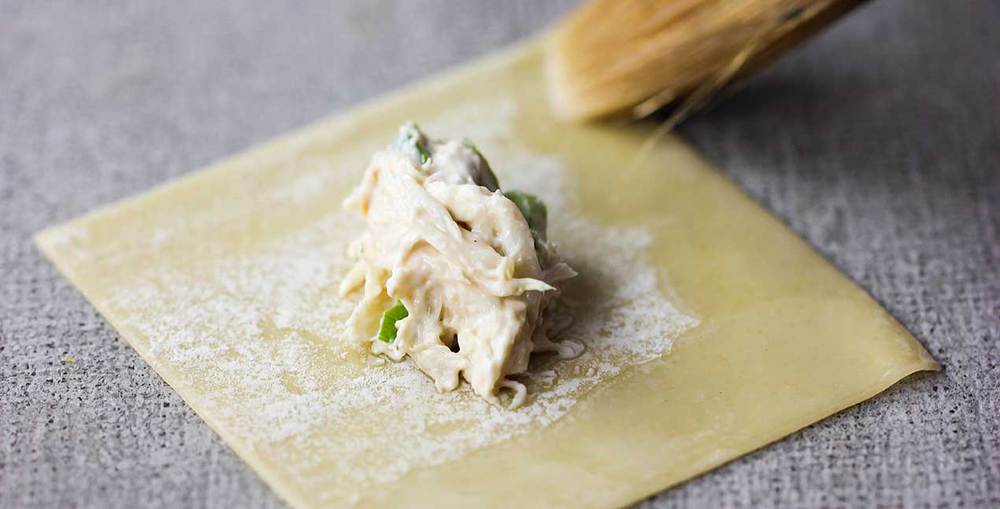 A brush adding water to the edges of a wonton wrapper for crab rangoon