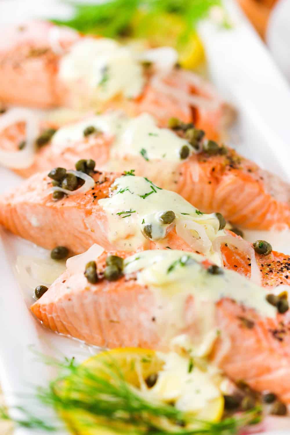 Poached salmon with capers and hollandaise sauce on a white platter