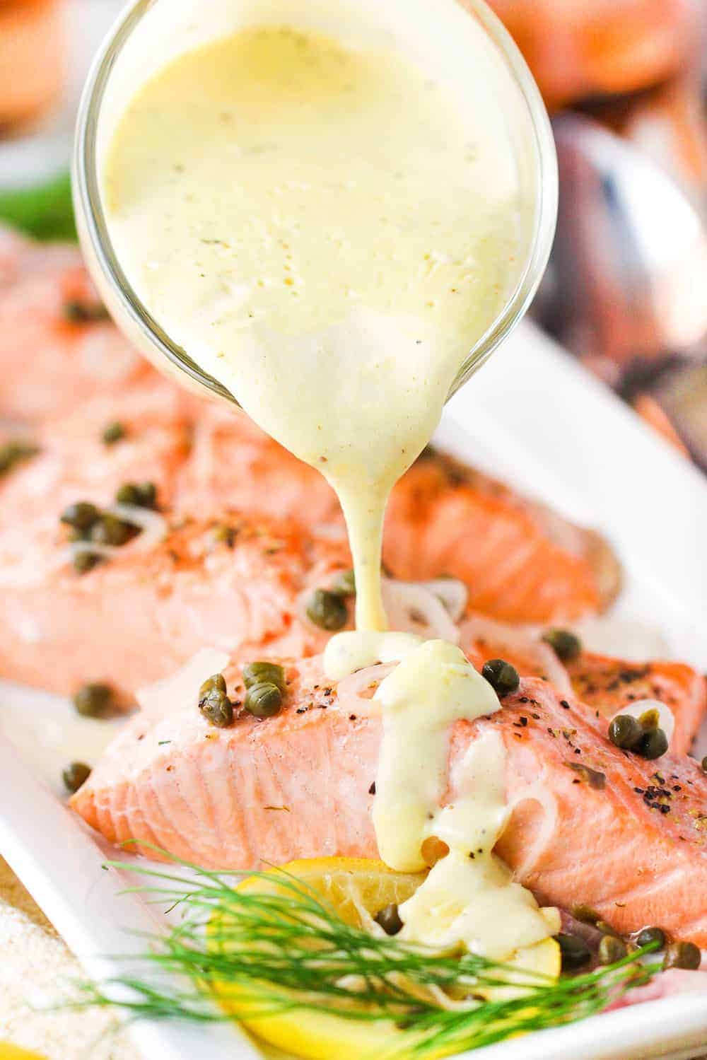 Poached salmon with hollandaise sauce being poured on top