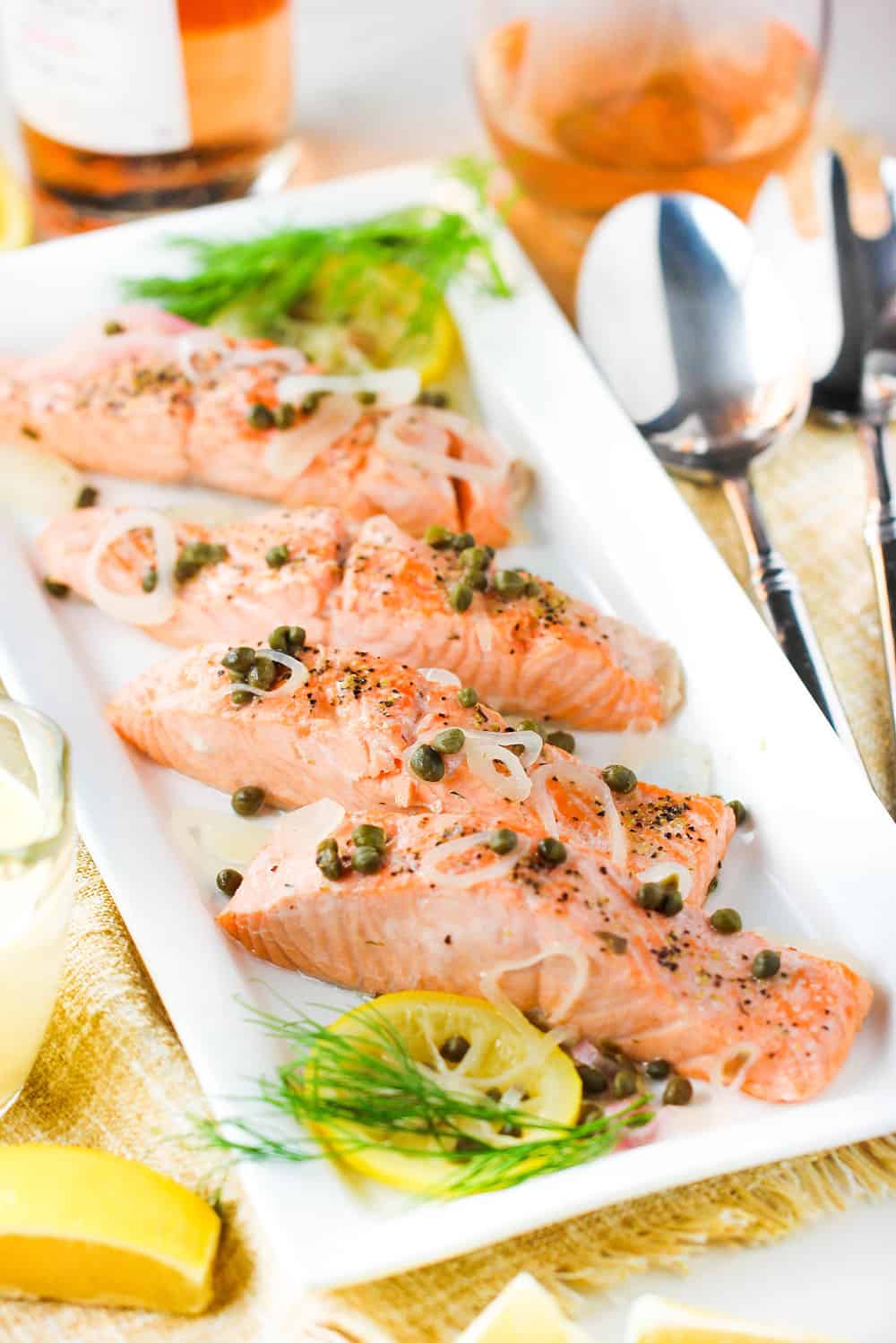 Poached salmon with capers and hollandaise sauce on a white platter