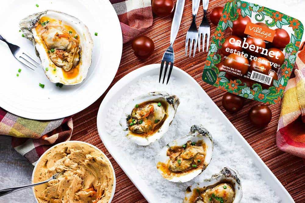 Grilled oysters with tomato butter next to a package of cherry tomatoes