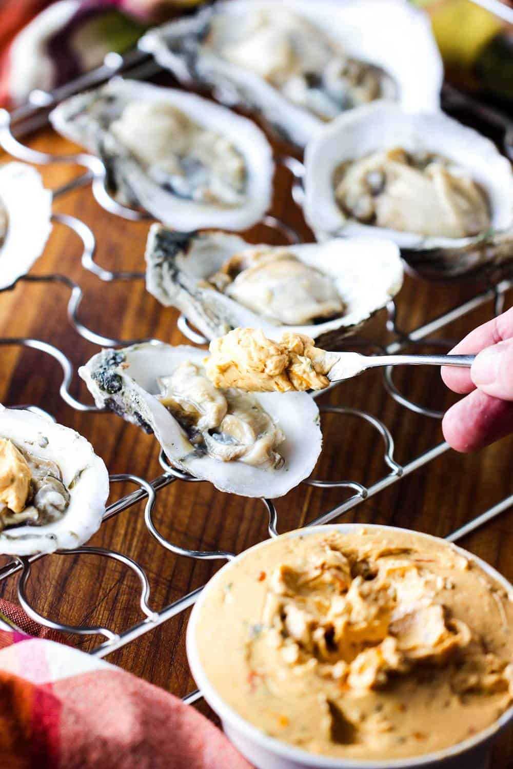 Tomato compound butter being added to fresh oysters