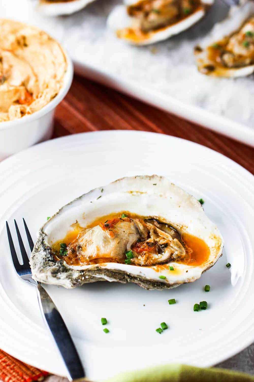 Grilled Oysters with Roasted Tomato Butter on a plate with rock salt