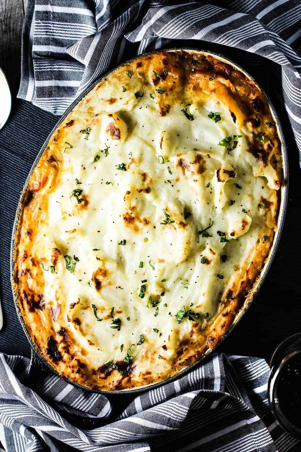 An overhead view of a baked shepherd's pie in a black dish.