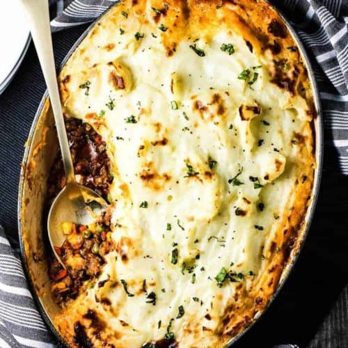 Homemade Sheperd's Pie in a black dish with a gold spoon in it.