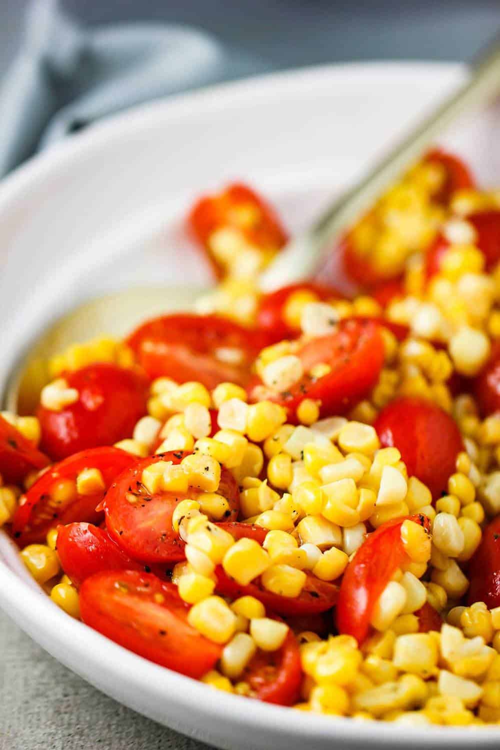 A white bowl of sautéed corn and tomato salad.