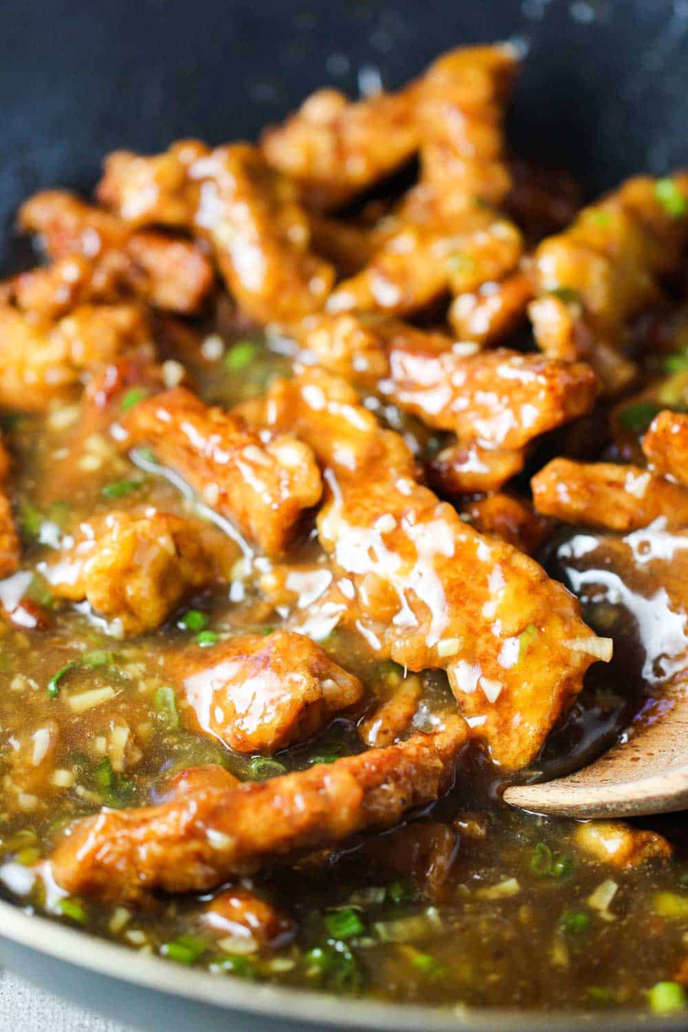 Fried pork strips in sweet and sour sauce in a wok for sweet and sour pork. 