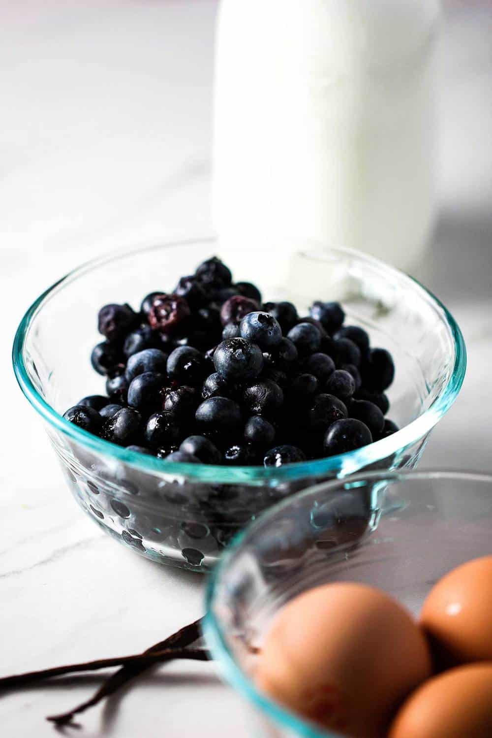 Blueberries in a clear bowl with eggs nearby