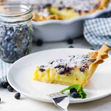 A slice of blueberry buttermilk pie on a white plate.