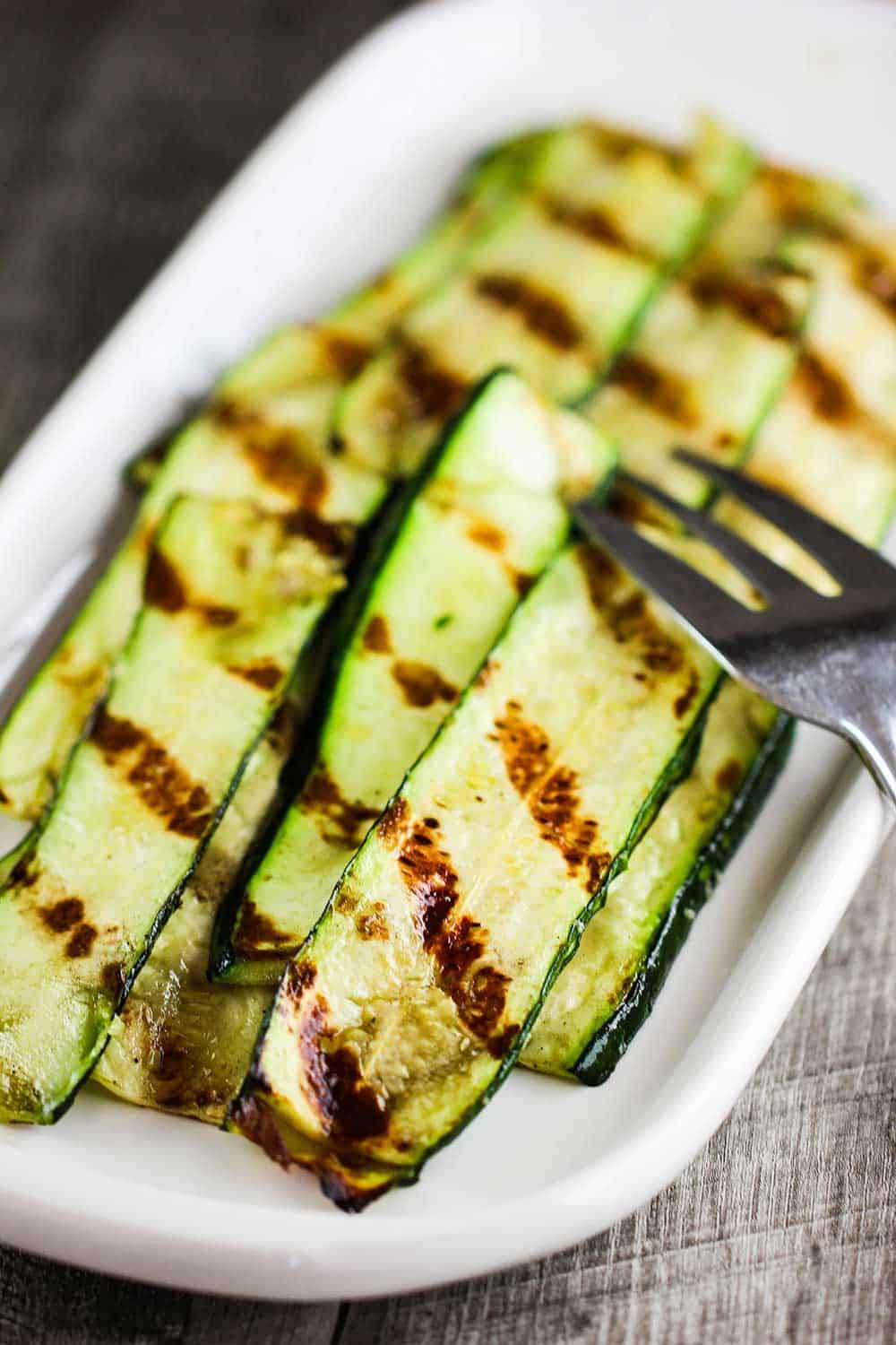 A white serving dish of grilled zucchini