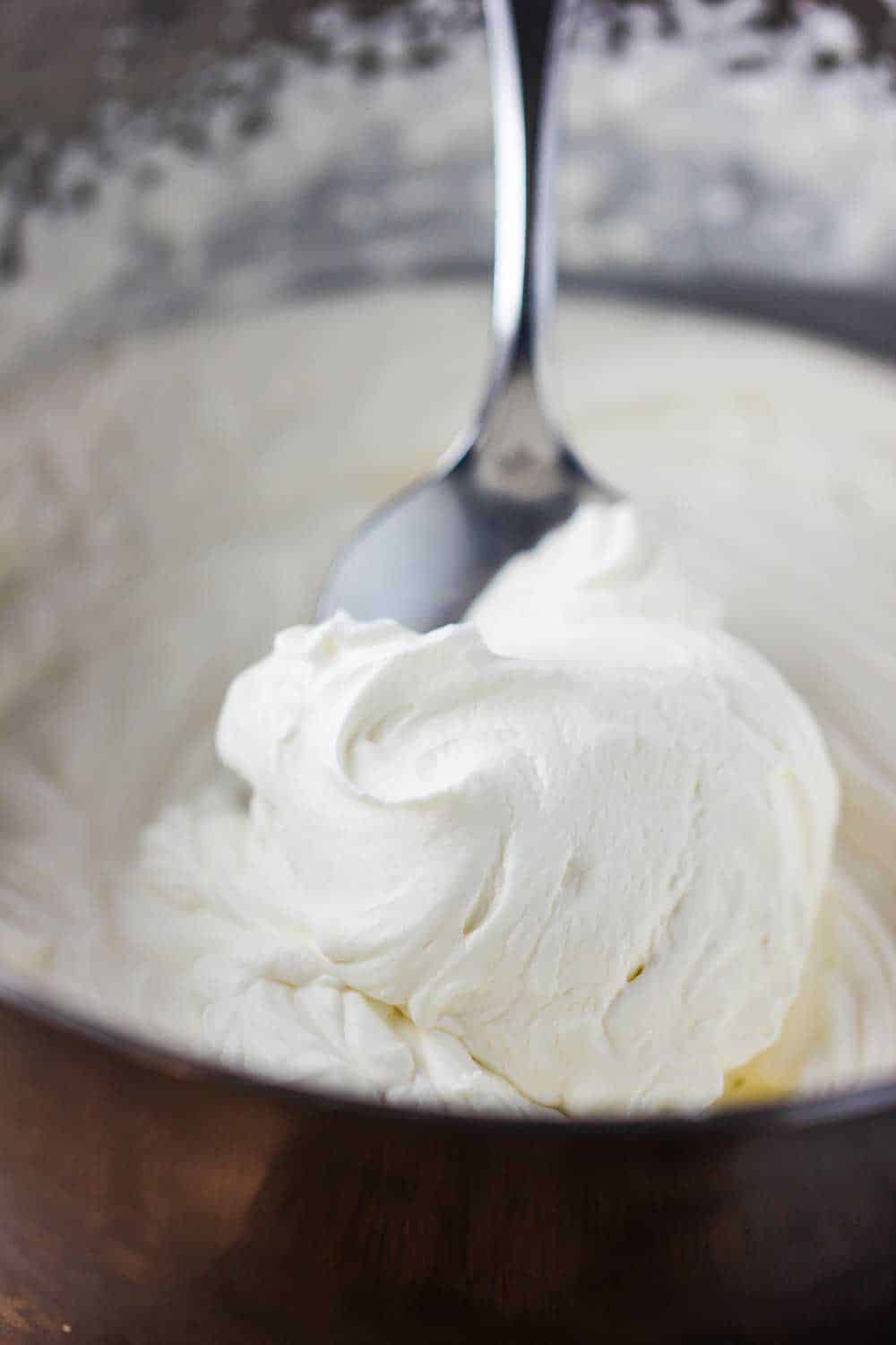 A metal bowl containing freshly prepared whipped cream