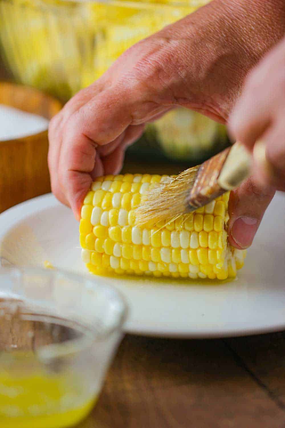 Brushing melted butter onto a corn niblet. 