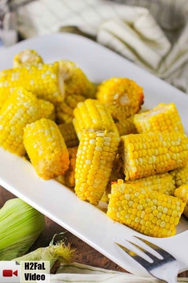 A white bowl holding slow-cooker corn on the cob.