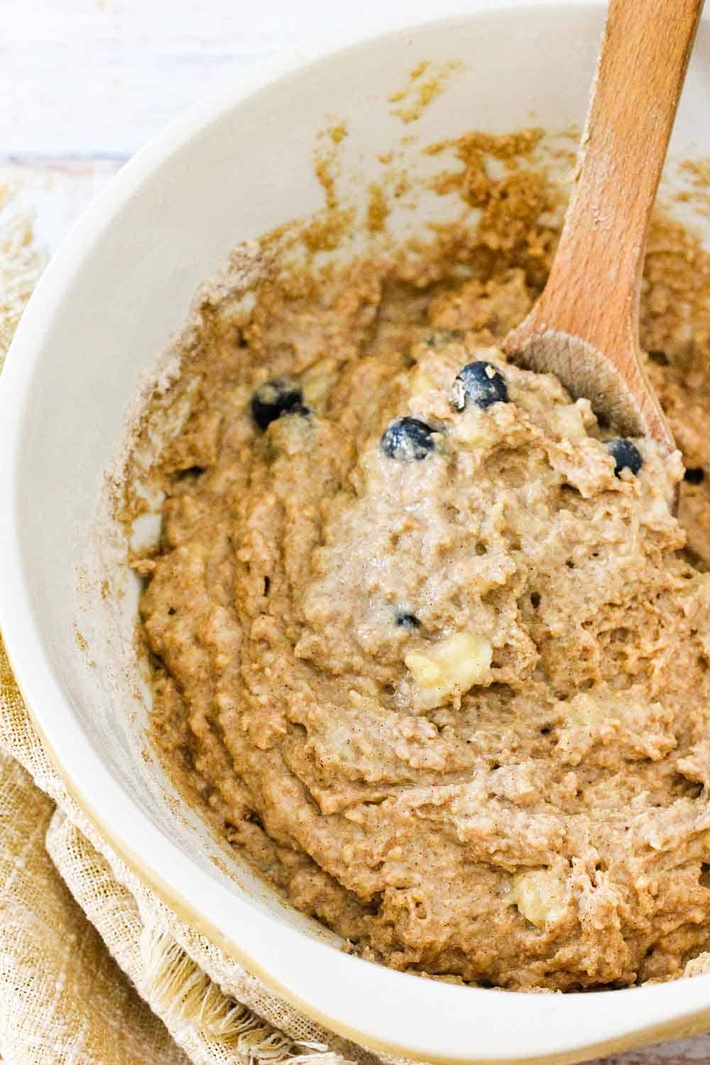 Mix the banana blueberry muffin batter in a large bowl with a wooden spoon. 