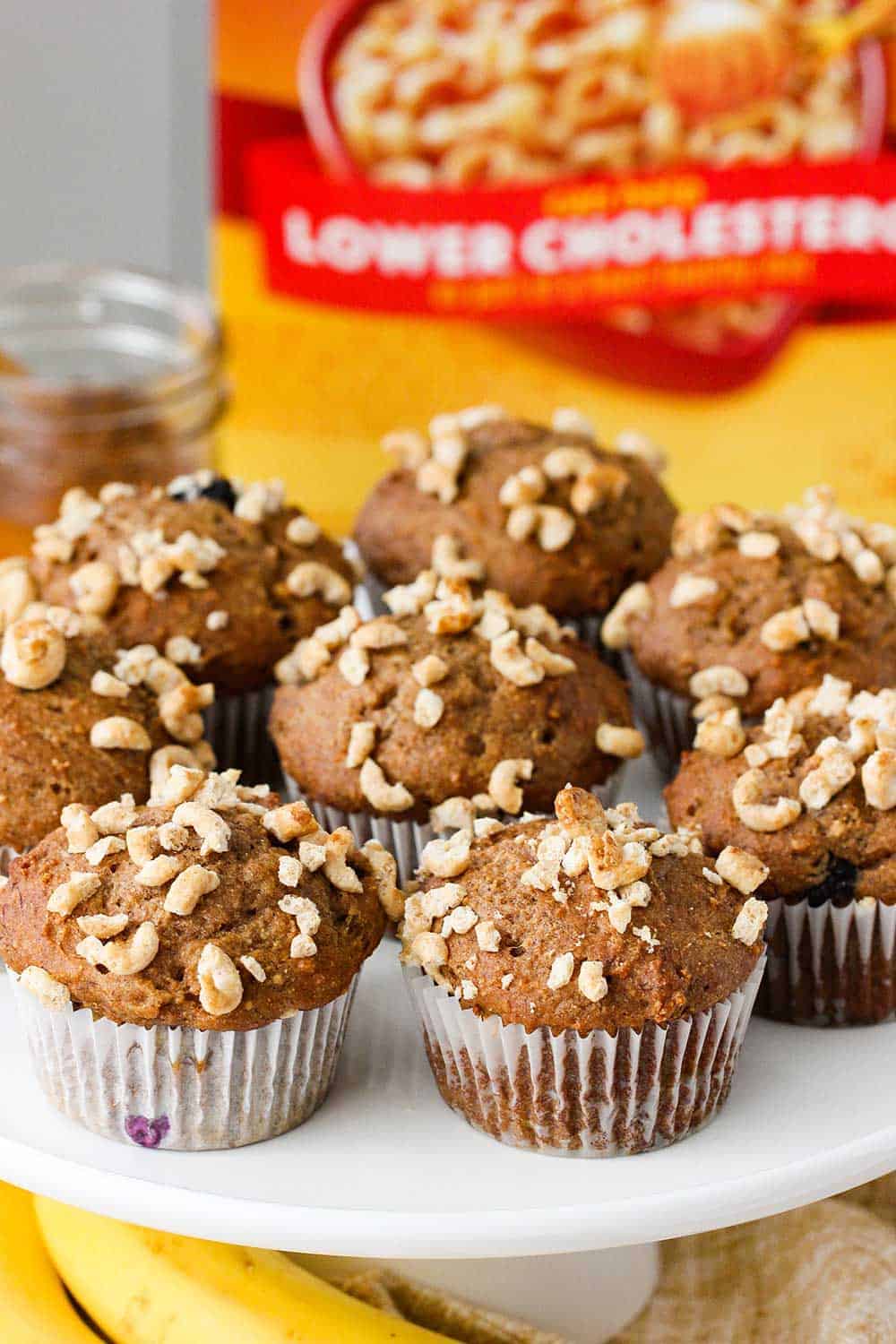 Place the baked banana blueberry muffins on a platter next to a box of Honey Nut Cheerios. 