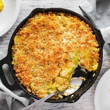 An overhead view of yellow squash casserole in a large black cast iron skillet.