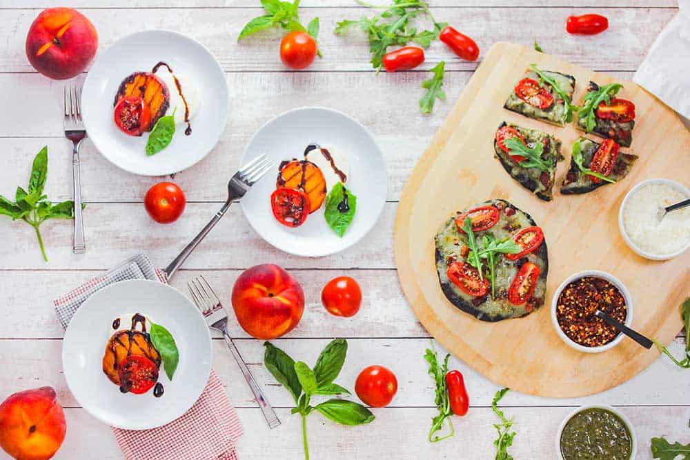 Individual servings of caprese salad next to a pizza paddle with portobello pizzas. 