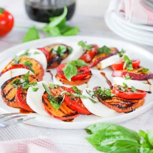 Caprese Salad with Grilled Peaches on a circular white platter.