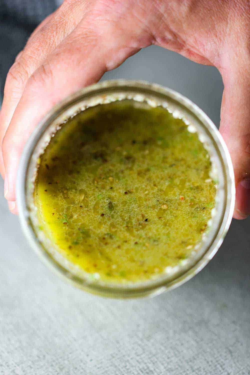 A view of looking into a jar containing homemade Italian dressing. 