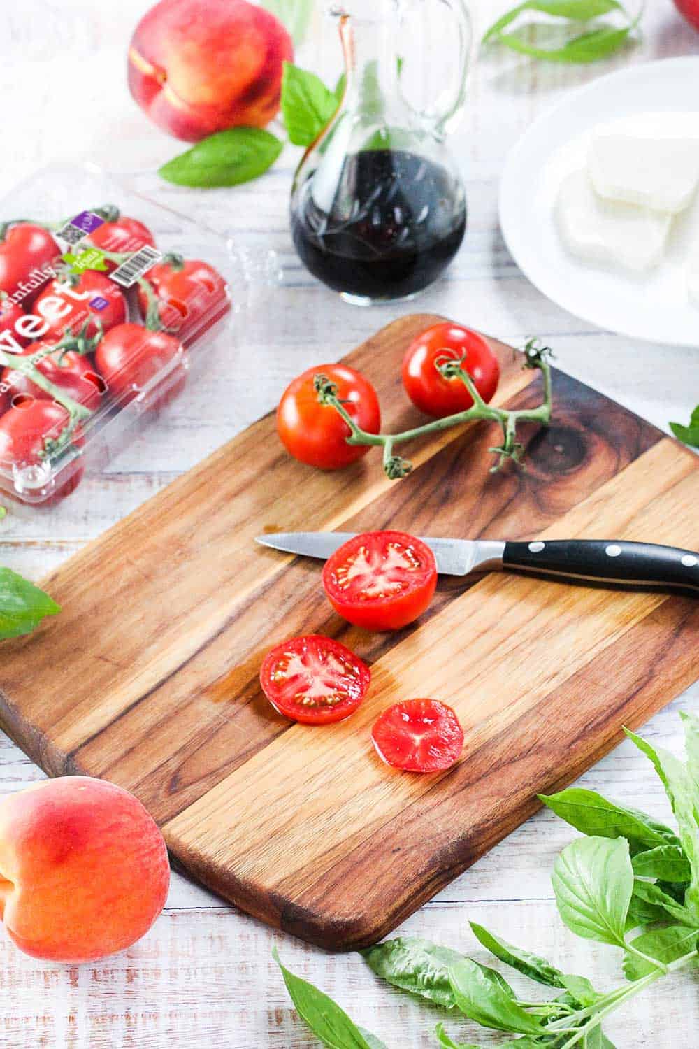 Sliced compari tomatoes on a wooden cutting board with basil nearby.