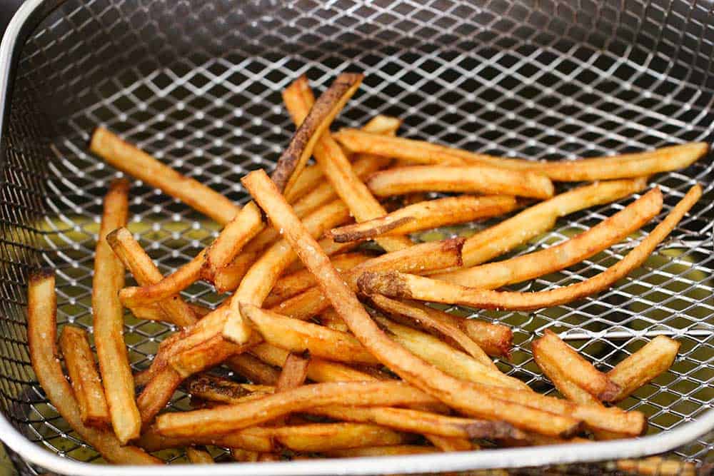 Homemade French fries in a basket of a deep fryer. 